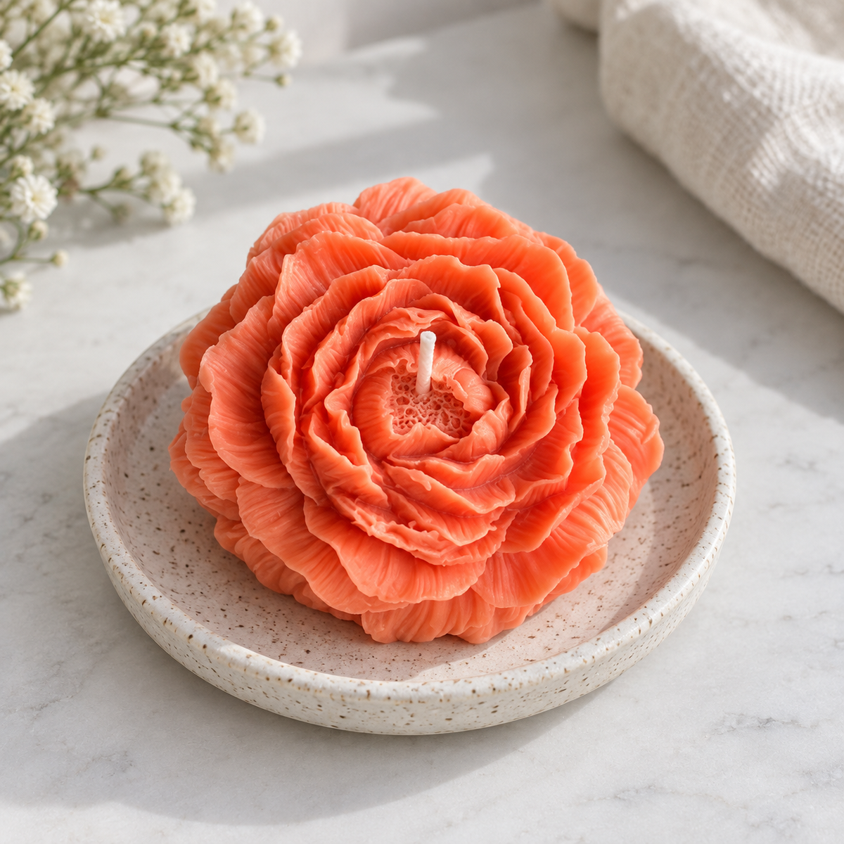 Peach Peony Flower Soy Wax Candle with visible wick on a speckled ceramic dish