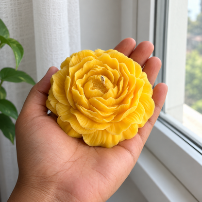 Yellow Peony Flower Soy Wax Candle held by hand beside a window with visible wick